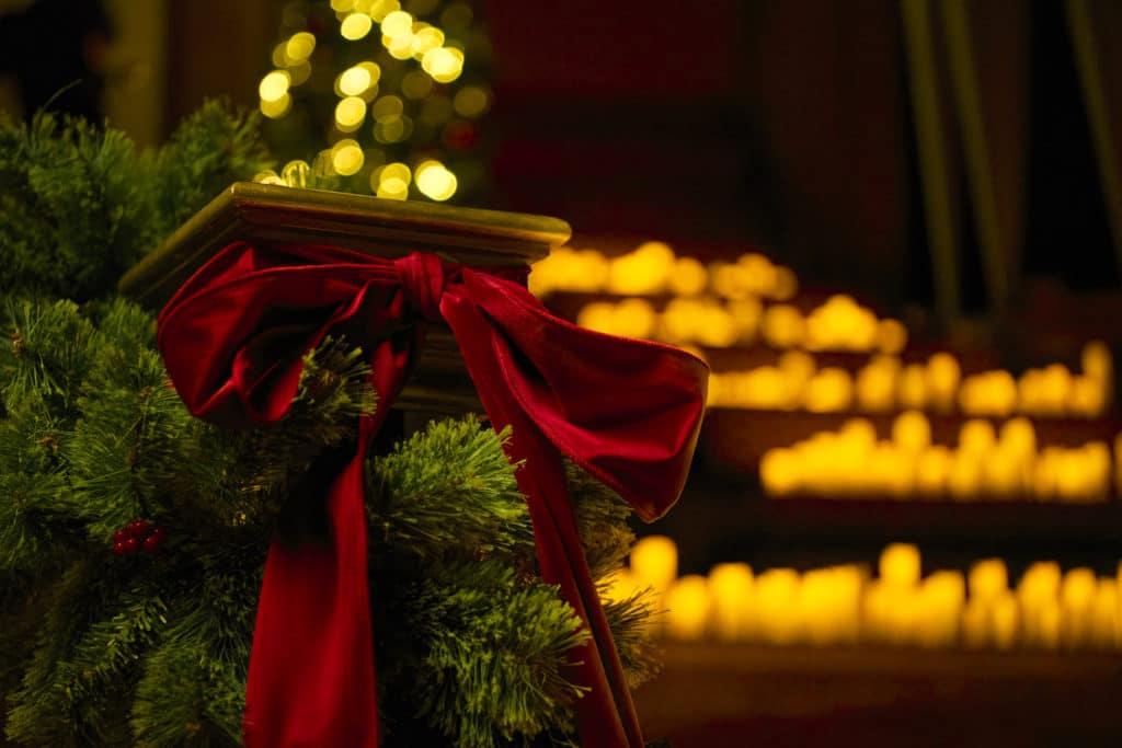 Photo d'un escalier décoré de branches de sapin et d'un ruban rouge pour un Candlelight spécial Noël