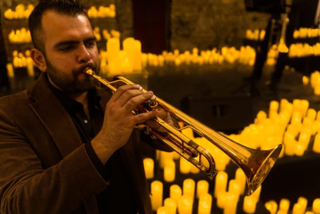Trompettiste jouant de la musique lors d'un concert Candlelight avec des bougies en fond